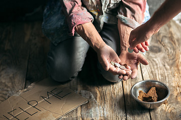 Image showing Male beggar hands seeking money on the wooden floor at public path way