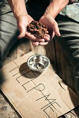 Image showing Male beggar hands seeking money on the wooden floor at public path way