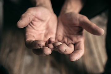 Image showing Male beggar hands seeking money on the wooden floor at public path way