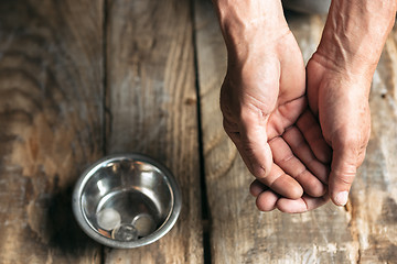 Image showing Male beggar hands seeking money on the wooden floor at public path way