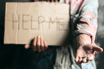 Image showing Male beggar hands seeking money on the wooden floor at public path way