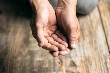 Image showing Male beggar hands seeking money on the wooden floor at public path way