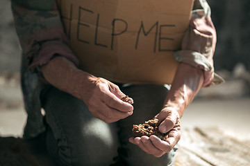 Image showing Male beggar hands seeking money on the wooden floor at public path way