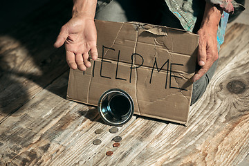 Image showing Male beggar hands seeking money on the wooden floor at public path way