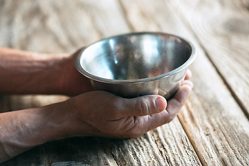 Image showing Male beggar hands seeking money on the wooden floor at public path way