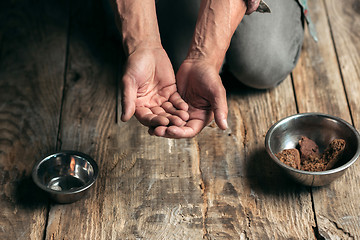 Image showing Male beggar hands seeking money on the wooden floor at public path way