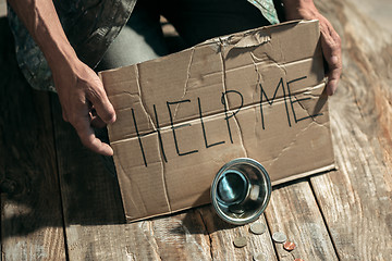 Image showing Male beggar hands seeking money on the wooden floor at public path way