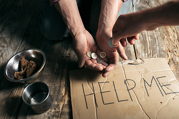 Image showing Male beggar hands seeking money on the wooden floor at public path way