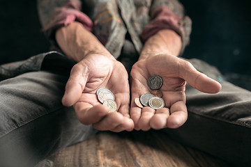 Image showing Male beggar hands seeking money on the wooden floor at public path way