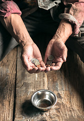 Image showing Male beggar hands seeking money on the wooden floor at public path way
