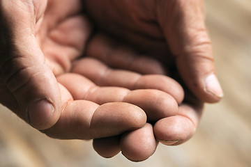 Image showing Male beggar hands seeking money on the wooden floor at public path way