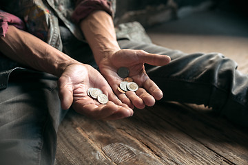 Image showing Male beggar hands seeking money on the wooden floor at public path way