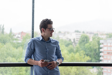 Image showing Businessman Standing In A Modern Building Near The Window With P