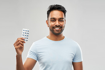 Image showing smiling indian man with pills over grey background