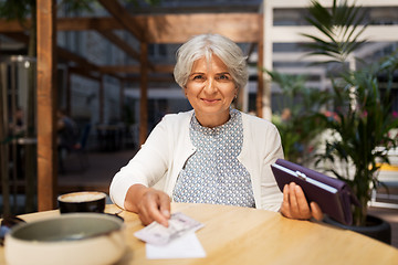 Image showing senior woman with money paying bill at cafe