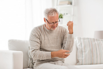 Image showing unhappy senior man suffering elbow pain at home