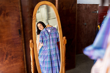 Image showing woman with dress at vintage clothing store mirror