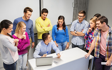 Image showing students and teacher with papers and laptop