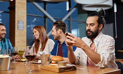 Image showing man messaging on smartphone at restaurant