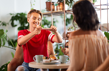 Image showing female friends drinking tea with cake at cafe