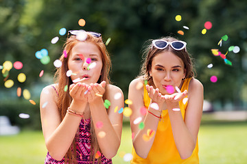 Image showing teenage girls blowing confetti off hands in park