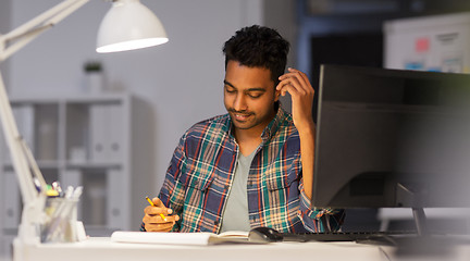 Image showing creative man with notebook working at night office