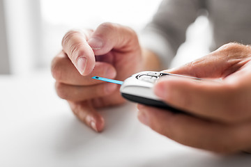 Image showing senior man with glucometer checking blood sugar