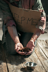 Image showing Male beggar hands seeking money on the wooden floor at public path way