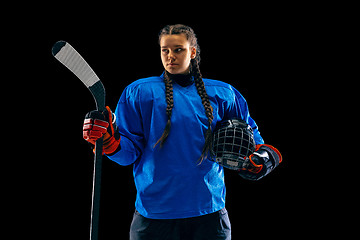 Image showing Young female hockey player with the stick isolated on black background