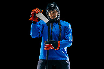 Image showing Young female hockey player with the stick isolated on black background