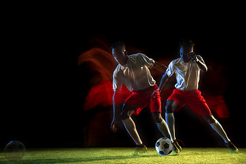 Image showing Male soccer player kicking ball on dark background in mixed light