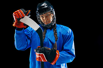 Image showing Young female hockey player with the stick isolated on black background