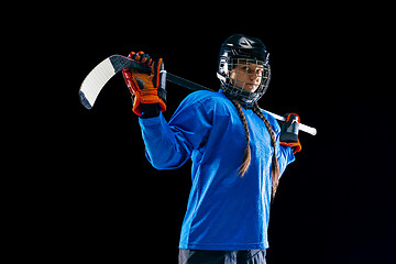 Image showing Young female hockey player with the stick isolated on black background