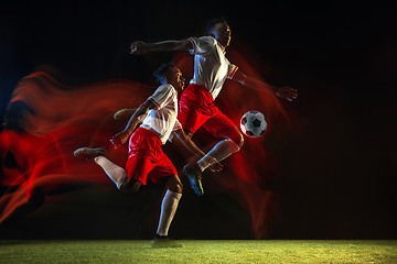 Image showing Male soccer player kicking ball on dark background in mixed light