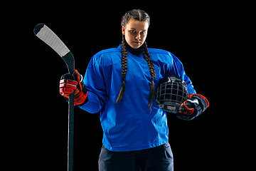 Image showing Young female hockey player with the stick isolated on black background