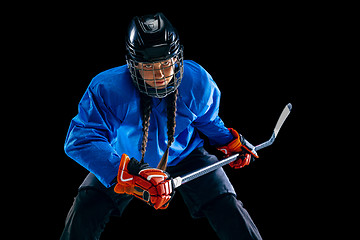 Image showing Young female hockey player with the stick isolated on black background