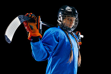 Image showing Young female hockey player with the stick isolated on black background