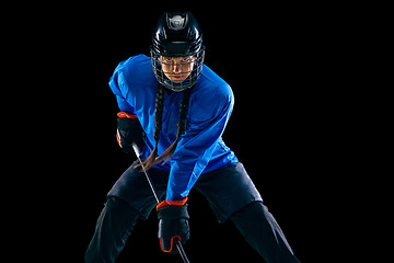 Image showing Young female hockey player with the stick isolated on black background