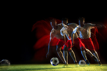 Image showing Male soccer player kicking ball on dark background in mixed light