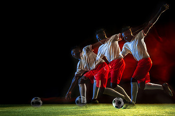 Image showing Male soccer player kicking ball on dark background in mixed light