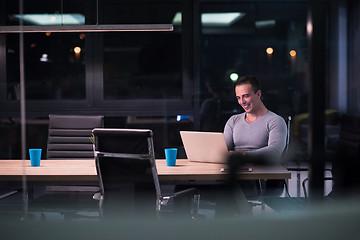 Image showing man working on laptop in dark office