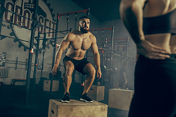 Image showing Man jumping during exercises in the fitness gym. CrossFit.