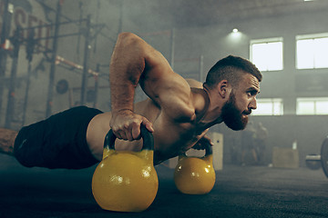 Image showing Fit young man lifting barbells working out in a gym