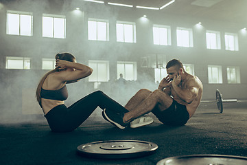 Image showing Man and woman during exercises in the fitness gym. CrossFit.