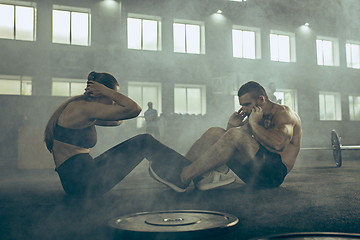 Image showing Man and woman during exercises in the fitness gym. CrossFit.