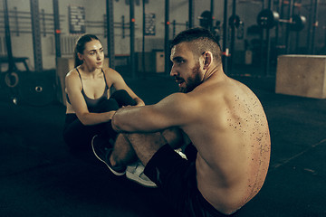 Image showing Man and woman during exercises in the fitness gym. CrossFit.