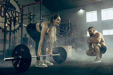 Image showing Fit young woman lifting barbells working out in a gym