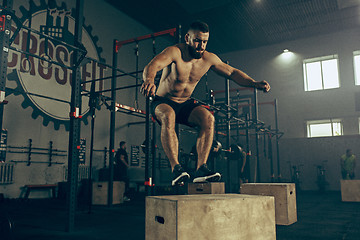 Image showing Man jumping during exercises in the fitness gym. CrossFit.