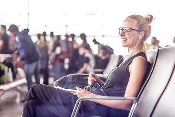 Image showing Female traveler using her cell phone while waiting to board a plane at departure gates at asian airport terminal.