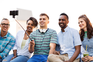 Image showing friends taking picture by on selfie stick in city